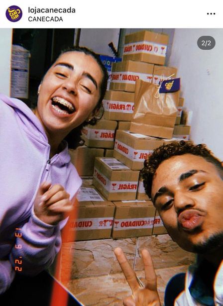 Dálet e Amós em selfie com uma pilha de caixas de pedidos