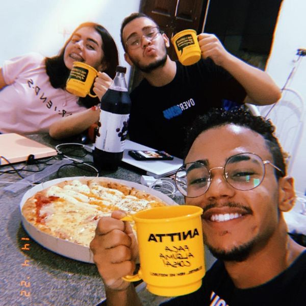 Três jovens sorrindo e brindando com canecas amarelas personalizadas