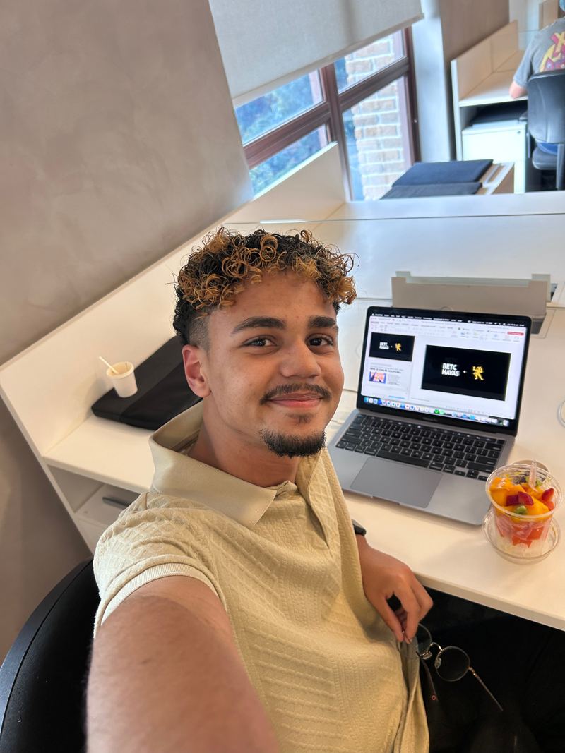 Selfie de Amós na mesa da agência, com adesivos da Therezópolis e da BETC Havas