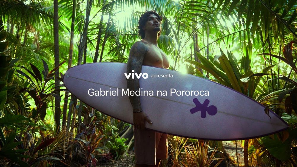Gabriel Medina segurando prancha com o boneco da Vivo na floresta: Vivo apresenta Gabriel Medina na Pororoca